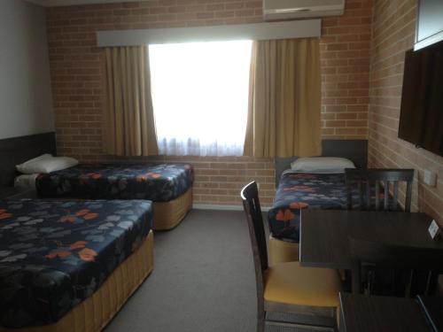 um quarto com duas camas e uma mesa e uma janela em Alexander The Great Motel em Windsor