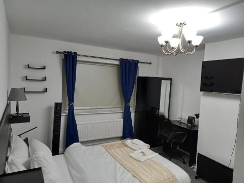 a bedroom with a bed with blue curtains and a desk at Cozzy Accommodation in Manchester