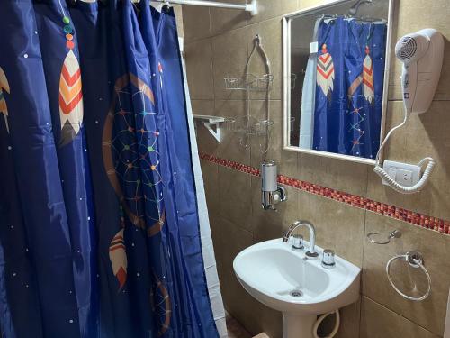 a bathroom with a sink and a shower curtain at AMANECER DE MONTAÑA in Capilla del Monte