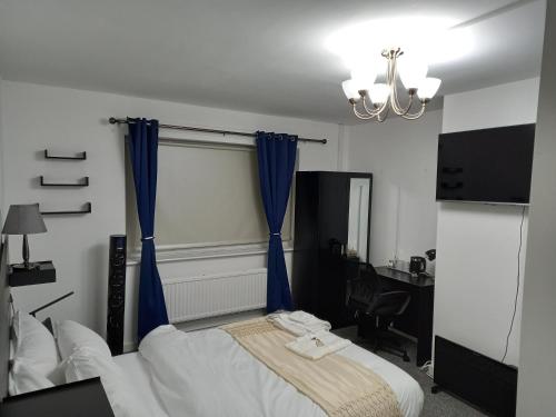 a bedroom with a bed with blue curtains and a desk at Cozzy Accommodation in Manchester