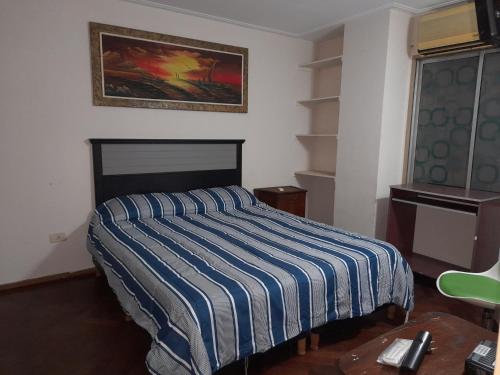 a bedroom with a bed with a striped blanket at Leo IV in San Fernando del Valle de Catamarca