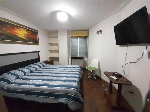 a bedroom with a bed and a flat screen tv at Leo IV in San Fernando del Valle de Catamarca