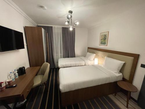 a hotel room with two beds and a desk at Hotel Casa Andalucia in Hallbergmoos