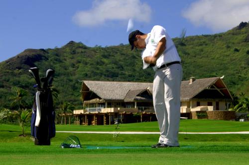 a man is standing on a golf course at Sofitel Kia Ora Moorea Beach Resort in Maharepa