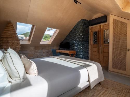 um quarto com uma grande cama branca e janelas em Azor Eco Lodge em São Vicente Ferreira
