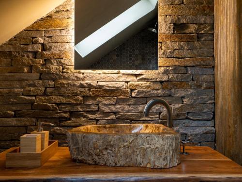 a bathroom with a stone wall and a sink at Azor Eco Lodge in São Vicente Ferreira