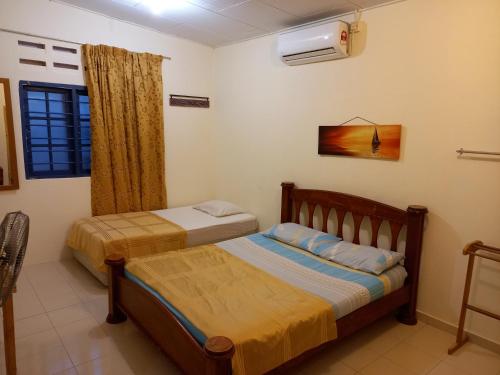 1 dormitorio con 2 camas y ventana en THE COTTAGE LANGKAWI en Pantai Cenang