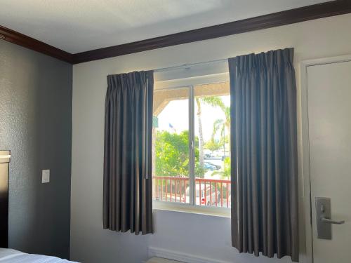 a bedroom with a window with blue curtains at Starlight Inn Huntington Beach in Huntington Beach