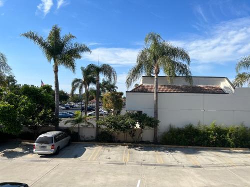 un coche aparcado en un aparcamiento con palmeras en Starlight Inn Huntington Beach, en Huntington Beach