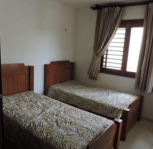 a bedroom with two beds and a window at TRIPLEX SOLAR CASA BRANCA in Guaramiranga