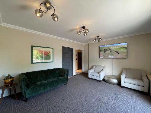 a living room with a green couch and two chairs at Hotel Casa Andalucia in Hallbergmoos