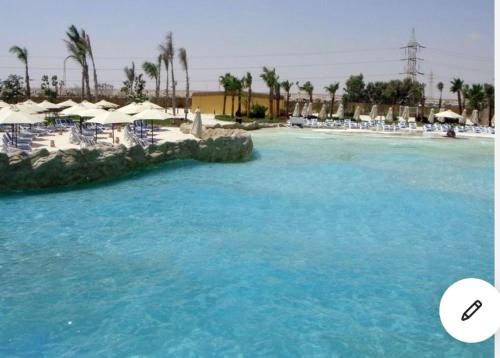 a swimming pool with blue water and umbrellas at Golf Porto marina in El Alamein