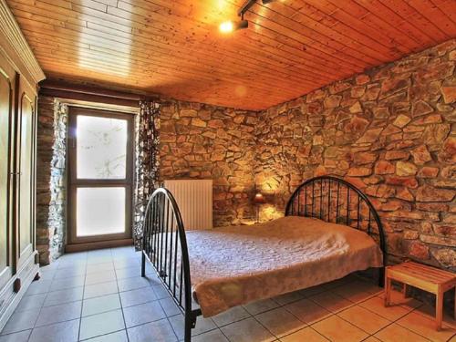 1 dormitorio con 1 cama en una pared de piedra en Rustic holiday home in Sainte-Ode with garden, en Sainte-Ode