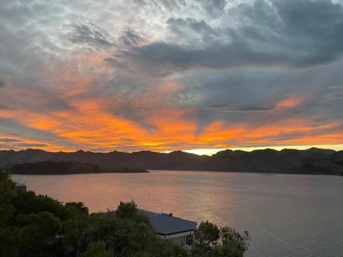 un coucher de soleil sur une grande étendue d'eau dans l'établissement Diamond Harbour Lodge, à Lyttelton