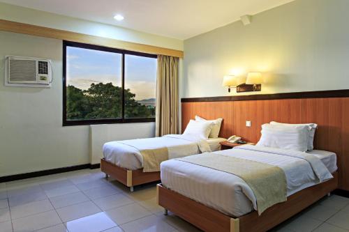 a hotel room with two beds and a window at The Orchard Cebu Hotel & Suites in Cebu City