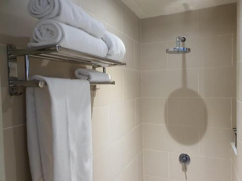 a bathroom with towels and a shower with a toilet at The Perfect Getaway @ Tamarind Suites, Netflix 300Mbps in Cyberjaya