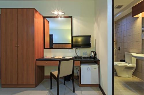 a bathroom with a desk with a sink and a toilet at The Orchard Cebu Hotel & Suites in Cebu City