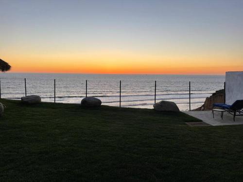 a bench sitting next to the ocean at sunset at Triton's Playhouse Beachfront in Primo Tapia