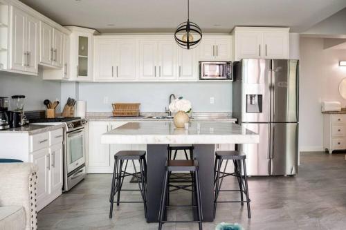 a kitchen with white cabinets and a kitchen island with stools at Triton's Playhouse Beachfront in Primo Tapia