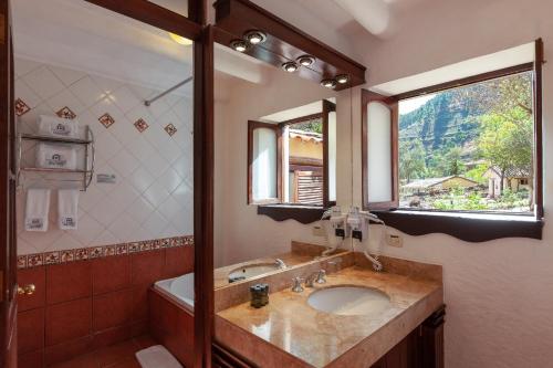 La salle de bains est pourvue d'un lavabo, d'une baignoire et d'une fenêtre. dans l'établissement Inti Punku Valle Sagrado Hotel, à Urubamba