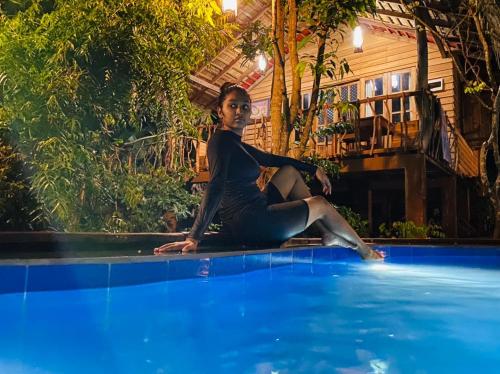 a woman sitting on the edge of a swimming pool at Habarana Tree house Mutu village in Habarana
