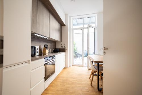 uma cozinha com armários brancos e uma mesa de madeira em Ko-Living - Beatles und Banksy Suites & Studios am Eselsbrunnen - Altstadt - Küche em Halle an der Saale