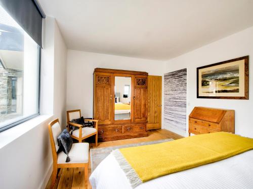 1 dormitorio con cama, tocador y espejo en Haven House, en Lochgilphead