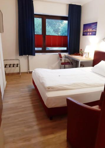 a bedroom with two beds and a desk and a window at Hotel Columbus und Glamping in Bremerhaven