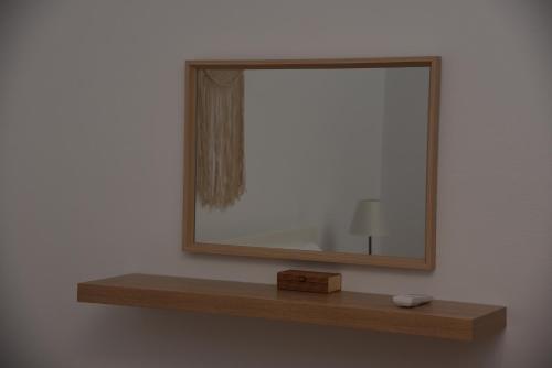 a mirror on a wall with a wooden shelf at J&B Maisonette House in Marmarion