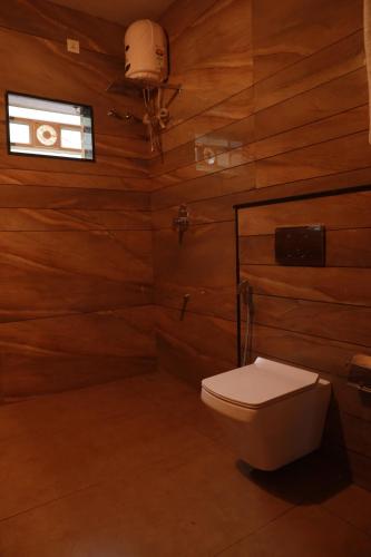a bathroom with a toilet in a wooden wall at Miracle Holidays in Mananthavady
