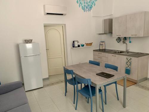 een keuken met een tafel en stoelen en een koelkast bij InterMezzo - located in the center of Salento equidistant from the 2 seas in Scorrano