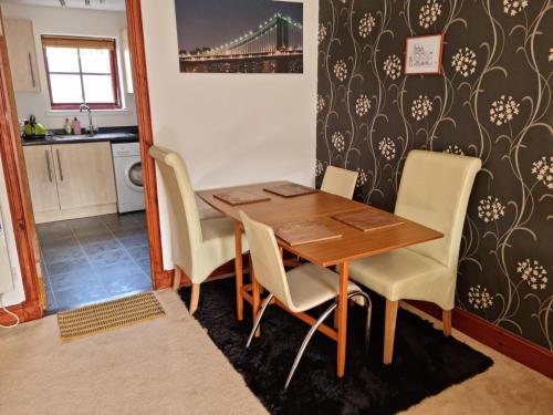 a kitchen and dining room with a wooden table and chairs at Superb 2 Bedroom Flat Tillicoultry in Tillicoultry