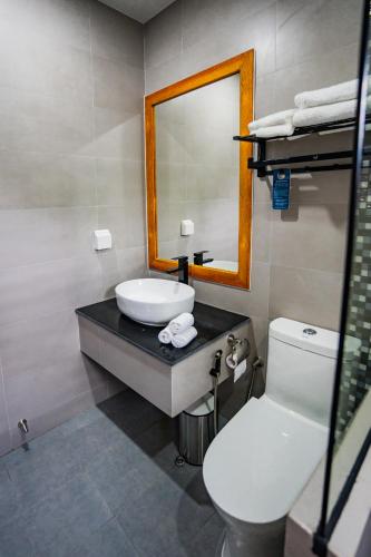 a bathroom with a sink and a mirror and a toilet at Maa Thundi in Fuvahmulah
