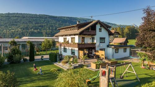 uma casa com um quintal com um parque infantil em Gästehaus Nassfeld em Tröpolach