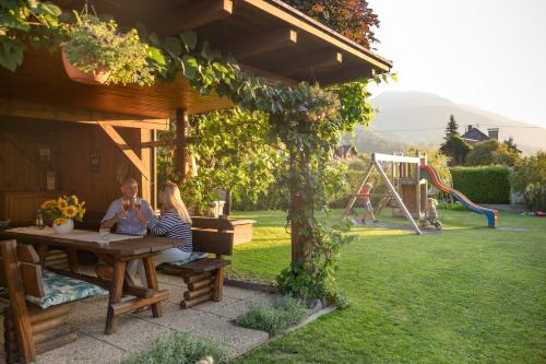 a man and woman sitting at a table in a garden at Gästehaus Nassfeld in Tröpolach