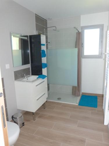 La salle de bains est pourvue d'un lavabo blanc et d'une douche. dans l'établissement Lumineuse maison neuve, cosy,67m², 2 Chambres/6 couchages 1km Lac, 200m du bourg. Vue paisible, sur la nature, à Saint-Pardoux