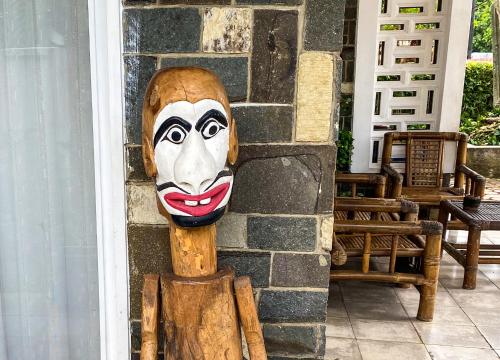 a wooden mask on the side of a building at Hostel Wees een Kind in Malang