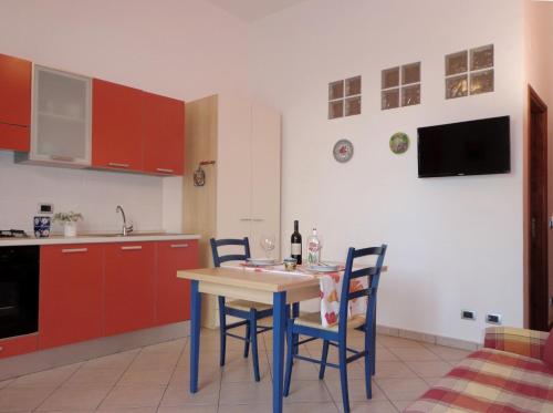 una cucina con tavolo, sedie e armadi rossi di Monolocale in Centro Tuttialmare Castellammare del Golfo Sicilia a Castellammare del Golfo