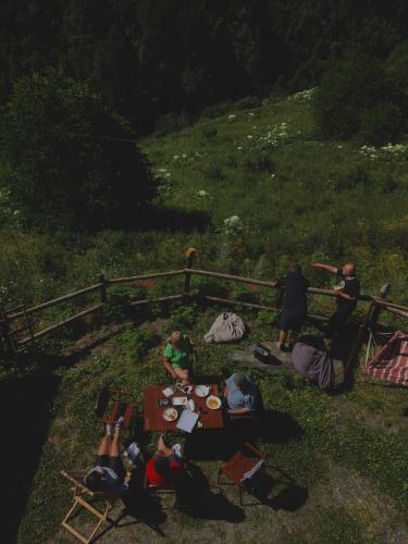 a group of people sitting around a table in the grass at Qaldea Resort in Ushguli