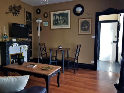 ein Wohnzimmer mit einem Tisch, Stühlen und einem TV in der Unterkunft Le Bon'Aparte - Hypercentre de Fontainebleau in Fontainebleau