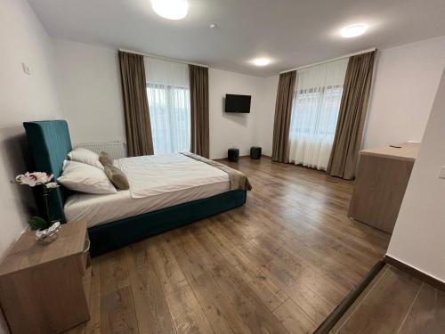 a bedroom with a bed and wooden floors and windows at Aparthotel Plevnei 3 in Cluj-Napoca