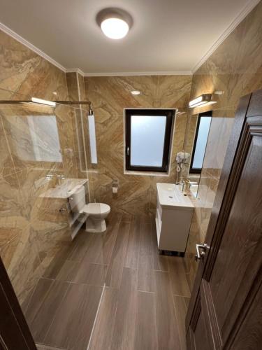 a bathroom with two sinks and a toilet and a mirror at Aparthotel Plevnei4 in Cluj-Napoca