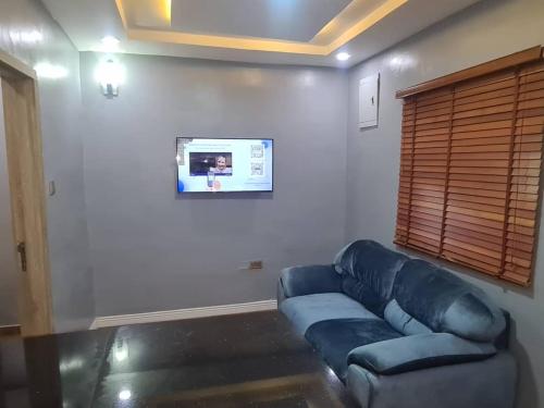 a living room with a blue couch and a window at Wine House, Maitama, Abuja in Abuja
