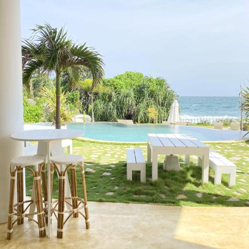 a table and chairs and a table and a pool at Belika Beach in Hiriketiya