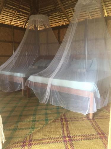 a bed with mosquito nets in a room at Prince John Beachfront Eco Bungalows and Restaurant in San Vicente