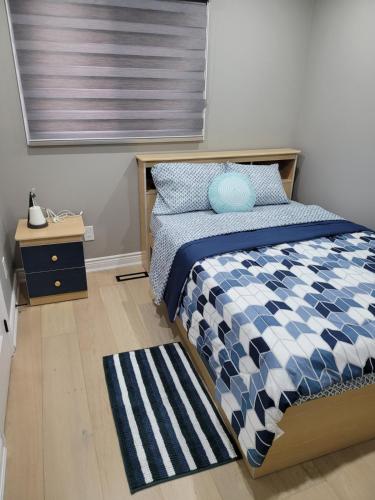 a bedroom with a bed with a blue and white comforter at Classic & Luxury Private Detached Entire Home with Free WI-FI & T.V in Brampton