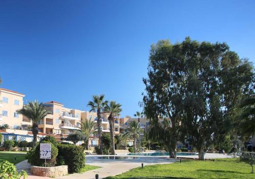a resort with a swimming pool and palm trees at 105 Kings Palace - Fabulous 2 Bed, 2 bath, Large Patio with Garden - Sea Views in Paphos City