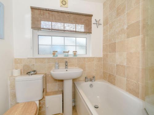 a bathroom with a sink and a toilet and a bath tub at Bluebell Cottage in Tavistock