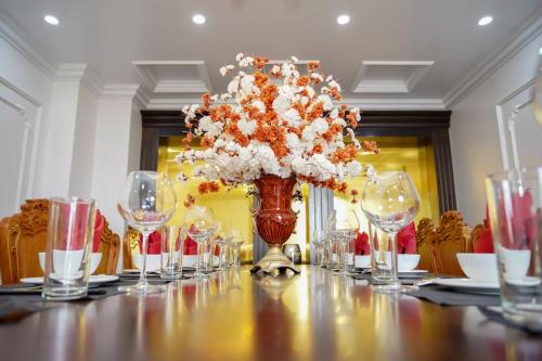 un lungo tavolo con bicchieri e un vaso con fiori di Khách sạn Hoa Đông a Châu Cầu