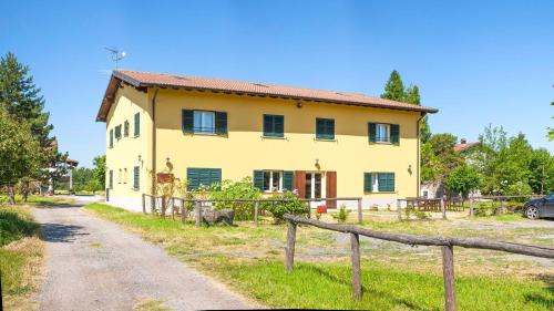 a yellow house with a fence next to a dirt road at Cascina Giacometta in Novi Ligure